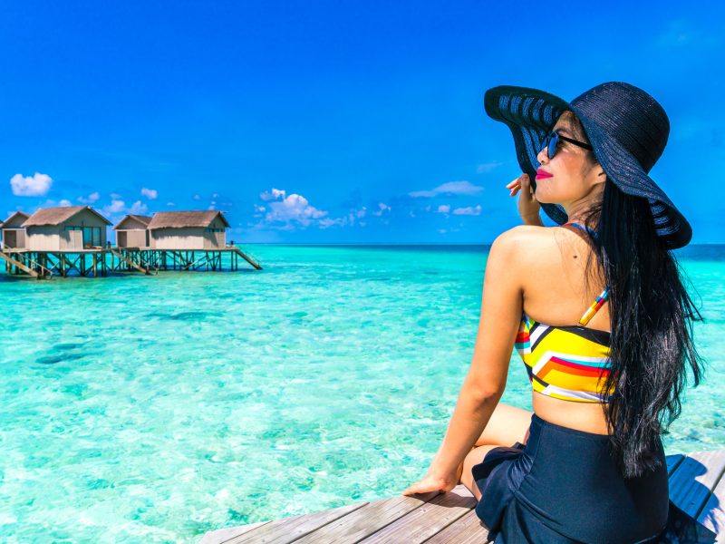 Wisatawan menikmati pantai Lombok dengan air laut jernih dan bungalow di atas laut, destinasi populer paket tour Lombok dan sewa mobil di Lombok